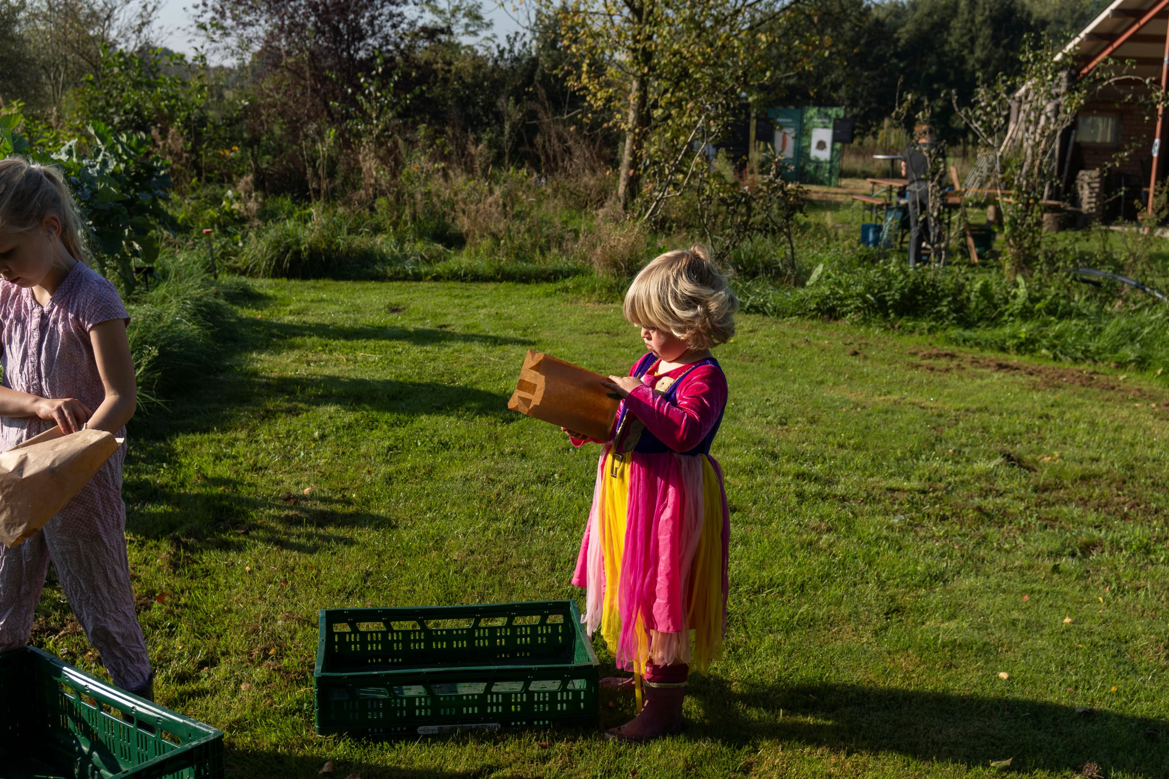 Kind in een prinsessenjurk met een oogsttas op de tuin